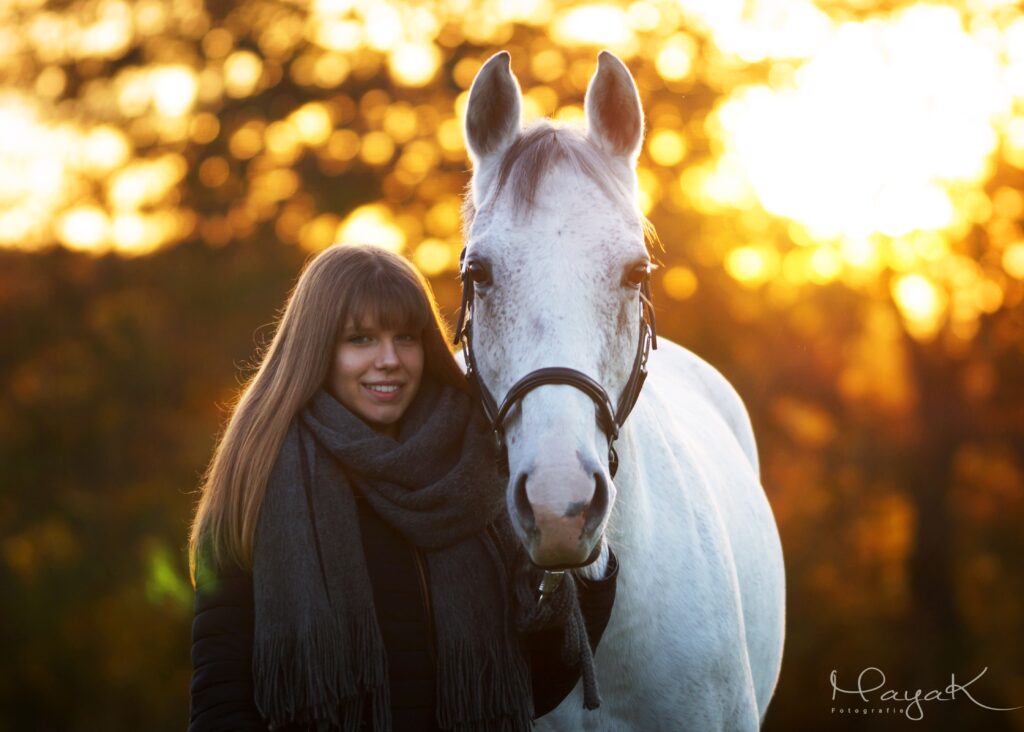 Fotografie von einem weißen Pferd und einem Mädchen im Sonnenuntergang
