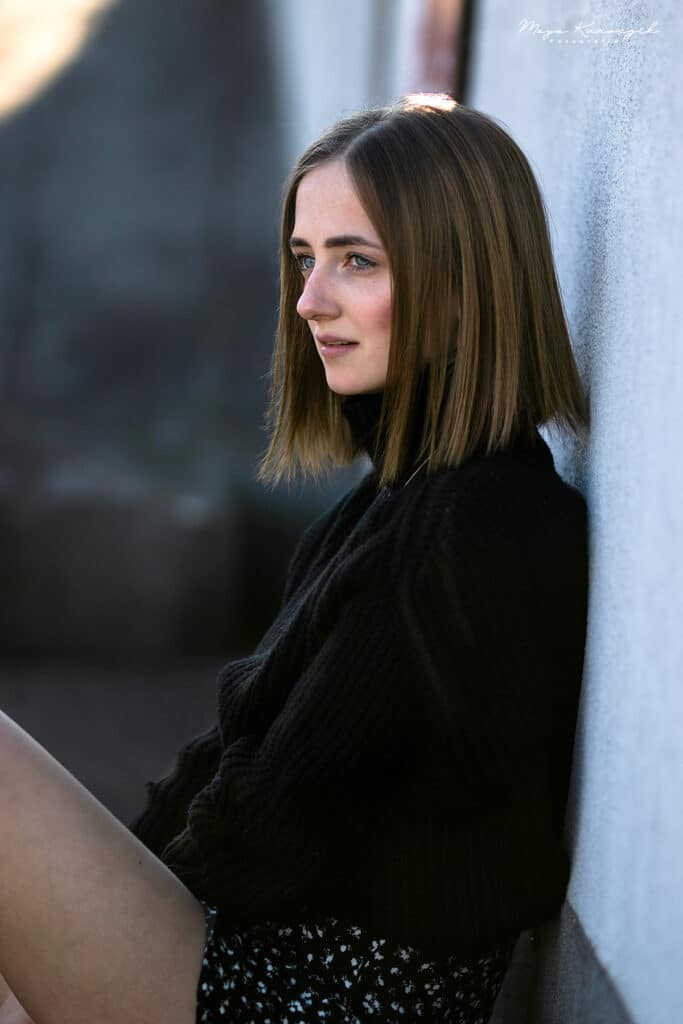 Portrait von einem Mädchen im sitzen an einer Wand