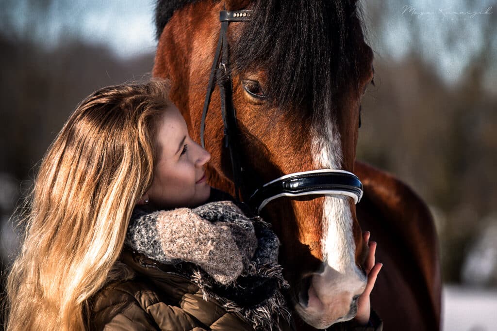 Nahaufnahme von einem blonden Mädchen mit ihrem Braunen Pferd