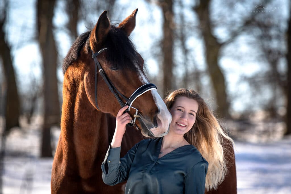 Portraitaufnahme von einem blonden Mädchen und ihrem wunderschönen Braunen Pferd mit heller Blesse