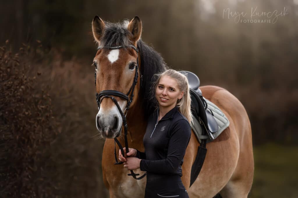 Blondes Mädchen mit ihrem Kaltblut im Reiteroutfit